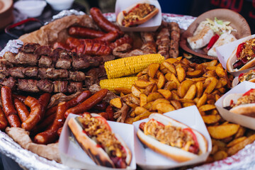 Food festival with food stall kiosk, open-air outdoor fair market, assortment of different traditional European grilled barbecued street food with sausages, bbq, chicken, pork and lamb on a large pan