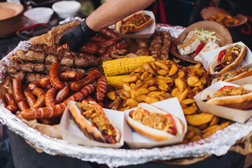 Food festival with food stall kiosk, open-air outdoor fair market, assortment of different traditional European grilled barbecued street food with sausages, bbq, chicken, pork and lamb on a large pan