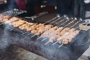 Food festival with food stall kiosk, open-air outdoor fair market, assortment of different traditional European grilled barbecued street food with sausages, bbq, chicken, pork and lamb on a large pan