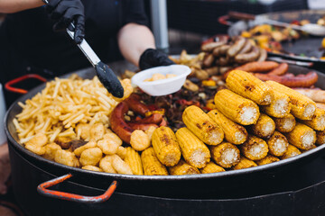 Food festival with food stall kiosk, open-air outdoor fair market, assortment of different traditional European grilled barbecued street food with sausages, bbq, chicken, pork and lamb on a large pan