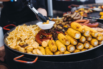 Food festival with food stall kiosk, open-air outdoor fair market, assortment of different traditional European grilled barbecued street food with sausages, bbq, chicken, pork and lamb on a large pan