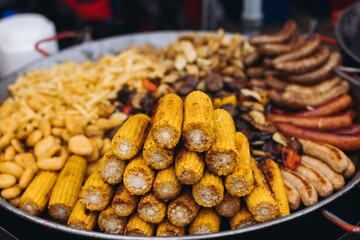 Food festival with food stall kiosk, open-air outdoor fair market, assortment of different traditional European grilled barbecued street food with sausages, bbq, chicken, pork and lamb on a large pan