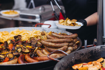 Food festival with food stall kiosk, open-air outdoor fair market, assortment of different traditional European grilled barbecued street food with sausages, bbq, chicken, pork and lamb on a large pan