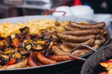 Food festival with food stall kiosk, open-air outdoor fair market, assortment of different traditional European grilled barbecued street food with sausages, bbq, chicken, pork and lamb on a large pan