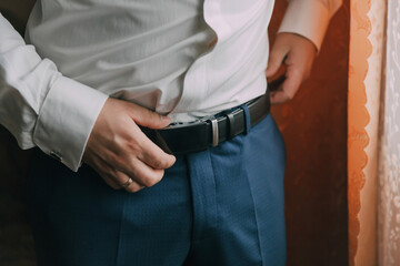 A man is wearing a blue belt and shirt. He is adjusting his belt