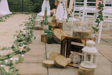 A wedding ceremony is taking place with a rustic theme. The bride and groom are walking down a path lined with flowers and lanterns