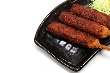 白背景の黒い皿に盛り付けた串カツ