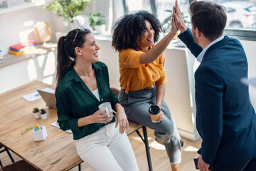 Business team celebrating good job while holding up their right hands on modern startup