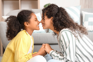Obraz premium Young African-American woman with her daughter touching noses at home