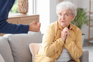 Young African-American female medical worker mistreating scared elderly woman in nursing home,...