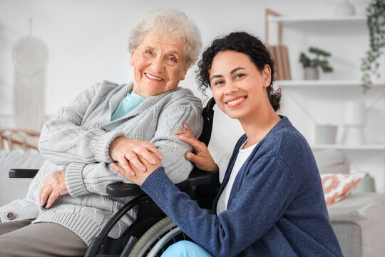 Young African-American female medical worker with elderly woman on wheelchair in nursing home