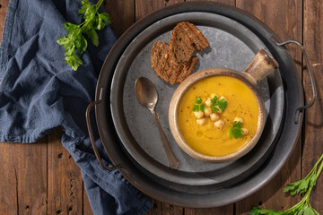 Pumpkin and chickpeas soup on brown rustic wooden background. Top view
