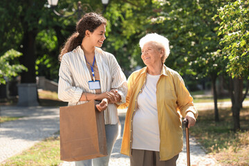 Young African-American female medical worker walking with elderly woman outdoors