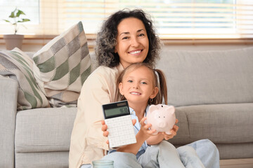 Little girl with her mother holding calculator and piggy bank at home