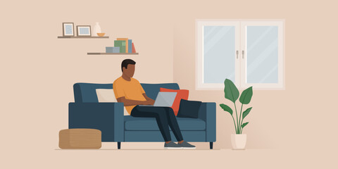 Man sitting on the couch and typing on a laptop
