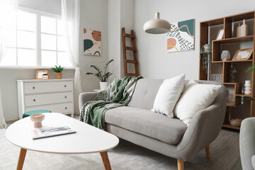 Interior of light living room with wooden ladder, sofa and shelf unit