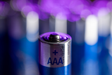 A close up of a AAA battery. The battery is sitting on a surface and is surrounded by other batteries