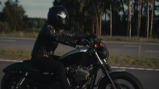 Man in black helmet and black leather jacket rides motorcycle at high speed along highway surrounded by trees. For touring motorcyclists tourer or cruiser is suitable. They are heavy and stable