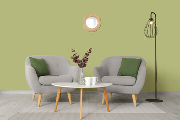 Interior of living room with mirror, grey armchairs and table