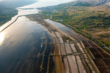 Aerial view of salt pans at sunset showcasing seawater evaporation and salt production