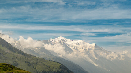 The Mont Blanc Massif Is Partially Obscured By Clouds On A Sunny Summer Day In The French Alps.