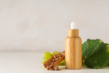 Bottle of cosmetic grape seed oil on white wooden table