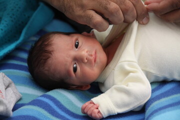 
Close-up of father's hands dressing his premature baby. Little baby looking at the camera. Paternity. Family care.