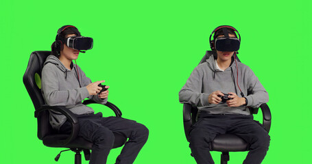 Gamer loving game with vr glasses and joystick while participating in online gaming contest with rivals. Asian man sitting on chair against greenscreen backdrop, enjoying his leisure time.