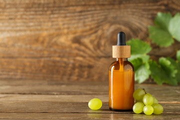Bottle of cosmetic grape seed oil on wooden background