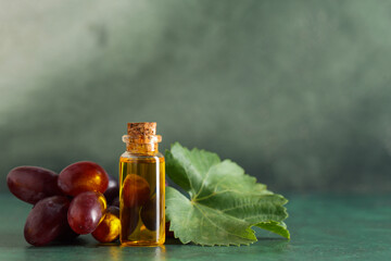 Bottle of cosmetic grape seed oil on green background