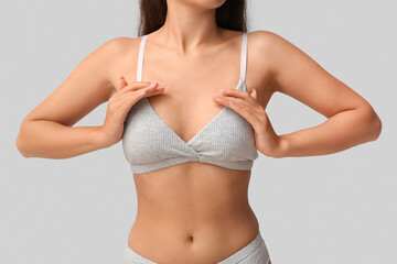 Young woman in bra on grey background, closeup