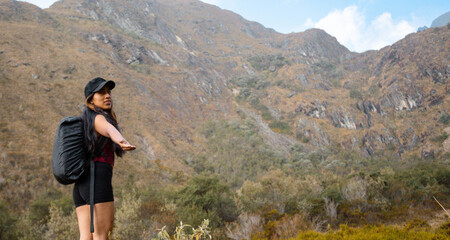Hermosas montañas y mujer joven  con short y mochila  en el camino concepto de turismo. Paisaje con chica deportiva con top en la cima de la montaña, bosque, colinas, cielo blancos con nubes, Viaje,