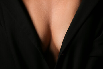 Young woman with beautiful breasts on black background, closeup