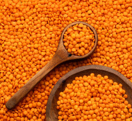 Lens culinaris - Raw red lentils in a bowl and spoon.