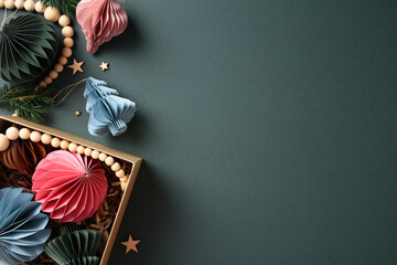 Hygge nordic style Christmas paper honeycomb ornaments in the box, wooden garland and stars on dark grey background. Sustainable Xmas decor, plastic free concept.