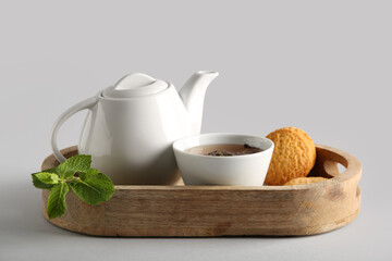 Beautiful composition with tea pot, cookies and wooden tray on white background