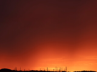 赤い朝焼けと山に立ち並ぶ送電鉄塔