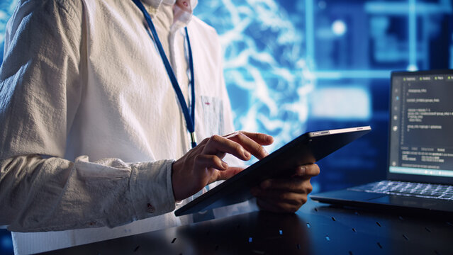 Computer scientist in data center, solving tasks on tablet while running programming scripts on laptop terminal. Certified engineer manipulating lines of code for AI applications development