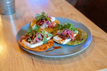 colorful open faced tortillas stacked high with cheese onions cilantro lime and sauces at a fine dining restaurant