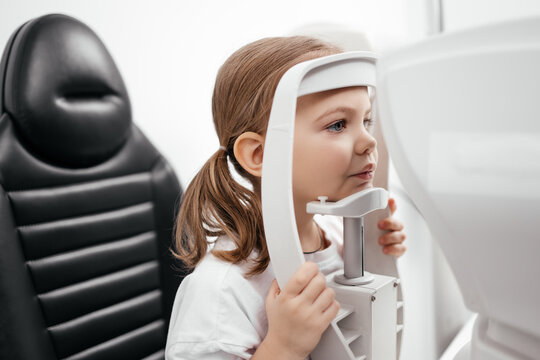 In a modern ophthalmology clinic, an ophthalmologist checks a little girl's vision using a binocular slit lamp. Advertisement for pediatric ophthalmology