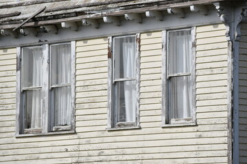 Fototapeta premium Victorian house, line of windows, faded yellow paint, peeling siding.