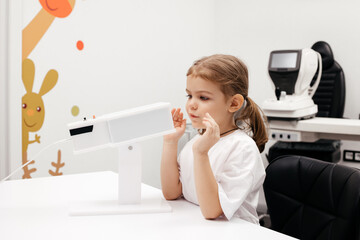 A young girl engages in orthoptic therapy using advanced vision stimulation equipment. Laser eye treatment for kids promotes recovery and enhances vision in a soothing environment. Advertising