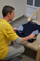 A man in a yellow shirt is cleaning a blue sweater.