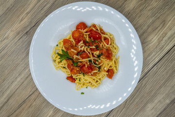 Overhead view of Tagliolini pasta served over pasta with basil, tomato, olive oil and cooked to perfection