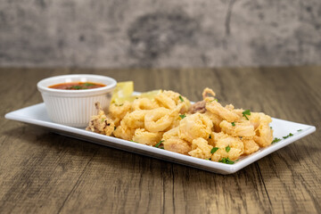 Overhead view of deep fried baby squid calamari rings served as and appertizer with a red sauce for dipping