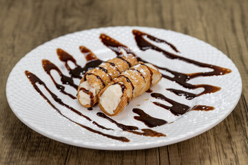 Tradional Italian dessert is served consisting of cannoli drizzled with chocolate syrup