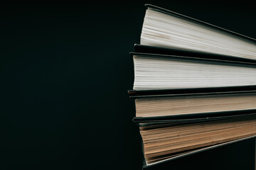 Books with black covers on a black background. Books about magic, mysticism and esotericism.Stack of books. Reading books. Reading and education.