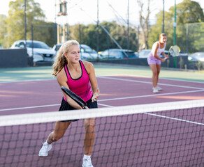 Obraz premium Female player playing tennis in tennis court outdoor behind the net