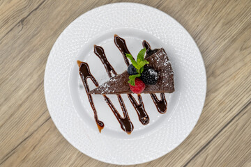 Overhead view of slice of bitter sweet chocolate cake with fruit topping and chocolate garnishment...