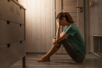 Sad woman in a dark room full of desperation thoughts. Portrait of thoughtful sad female alone....